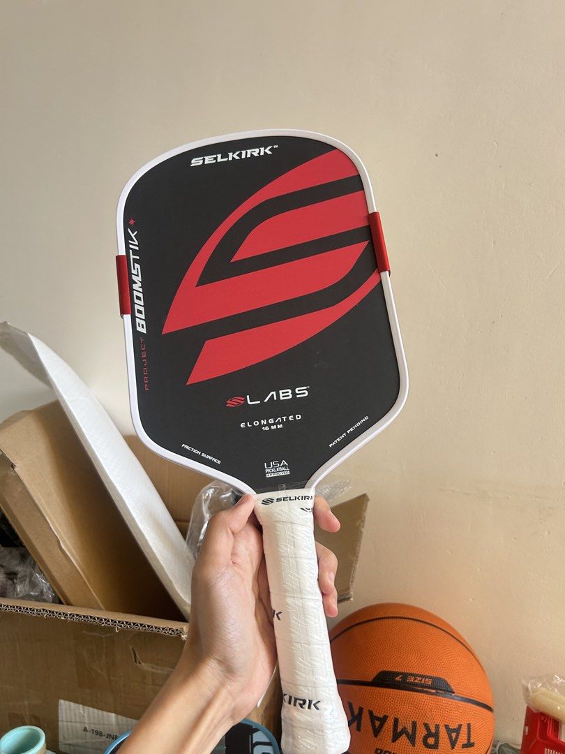 Selkirk Boomstik Pickleball Paddle (Category: Racket and Ball Sports) located in Cavite. Submitted by _schmyla (Listing ID 1469888379, Image 1). Description: - Model: Selkirk Labs Project 003 Boomstik - Shape & Core: Elongated shape with 16 mm thickness - Design: Striking red and black graphics with a clean white edge guard - Enhancements: Custom edge weights attached on both sides for extra power - Grip: Securely wrapped white grip tape on the h