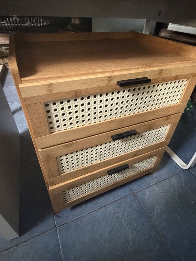 side table (Category: Shelves, Cabinets & Racks) located in Makati City. Submitted by sausage011 (Listing ID 1469843904, Image 1). Description: - Material: Quality wood with clean finish - Storage: 3 spacious drawers with off-white woven rattan front panels - Details: Chic dark rectangular pull handles and raised edges on the top surface - Versatile Size: Compact design fits perfectly under desks or beds - Condition: Good as new, ready for your h