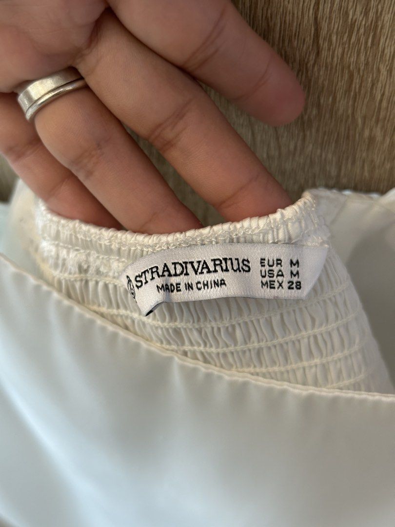 Stradivarius White Satin Tie Back Crop Top Size M (Category: Sleeveless) located in Pateros City. Submitted by overandout. (Listing ID 1469841910, Image 3). Description: - Brand: Stradivarius - Color: White - Size: Medium - Material: Smooth satin fabric - Design: Tie-back closure with smocked back panel, adjustable spaghetti straps, and chic pointed hem - Condition: Excellent pre-loved condition.