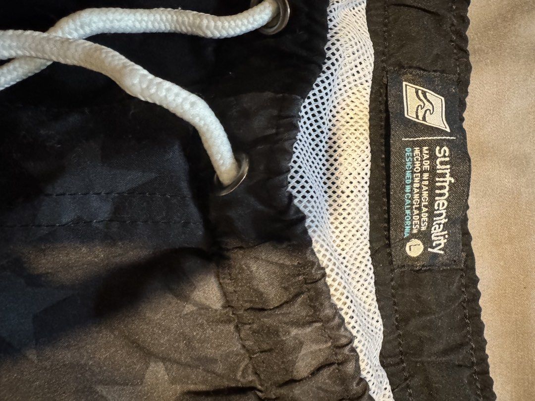 Surfmentality Black/ Grey Swim Trunks Size L (Category: Swim Trunks & Board Shorts) located in Taguig. Submitted by dependingonvibe (Listing ID 1469784443, Image 2). Description: - Brand: Surfmentality - Color: Black with subtle USA flag-inspired stripe and star pattern - Size: Large (Waist: ~17 inches, Length: ~16.5 inches) - Details: Elastic waistband, white adjustable drawstring, comfortable white mesh lining - Extra: Stylish round branded pat