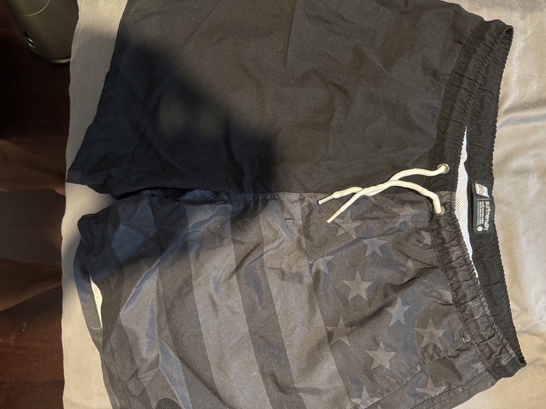 Surfmentality Black/ Grey Swim Trunks Size L (Category: Swim Trunks & Board Shorts) located in Taguig. Submitted by dependingonvibe (Listing ID 1469784443, Image 1). Description: - Brand: Surfmentality - Color: Black with subtle USA flag-inspired stripe and star pattern - Size: Large (Waist: ~17 inches, Length: ~16.5 inches) - Details: Elastic waistband, white adjustable drawstring, comfortable white mesh lining - Extra: Stylish round branded pat