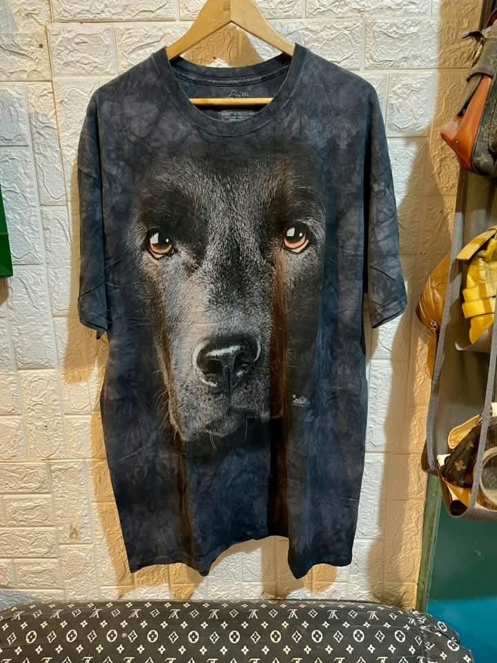 The Mountain Black Dog Face Print Graphic Tee (Category: Tshirts & Polo Shirts ) located in Manila. Submitted by carlosrexc26753 (Listing ID 1469826018, Image 1). Description: - Style: Graphic t-shirt with a bold black dog face print - Wash: Dark grey and black tie-dye effect - Fit & Comfort: Relaxed fit made from soft, breathable cotton - Details: Short sleeves, crew neck - Size: 2XL (marked on inner neck label) - Condition: Brand new / Excellen