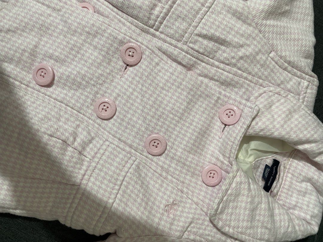 Tommy Hilfiger Pink Houndstooth Coat 12 Months (Category: Babies & Kids Fashion) located in San Fernando. Submitted by agustinjonna (Listing ID 1469879130, Image 3). Description: - Brand: Tommy Hilfiger - Item: Baby girls houndstooth coat - Color: Pink and white - Size: 12 months - Design: Double-breasted front with branded pink buttons and small embroidered logo near the pocket - Interior: Fully lined in smooth white satin - Condition: Excellent