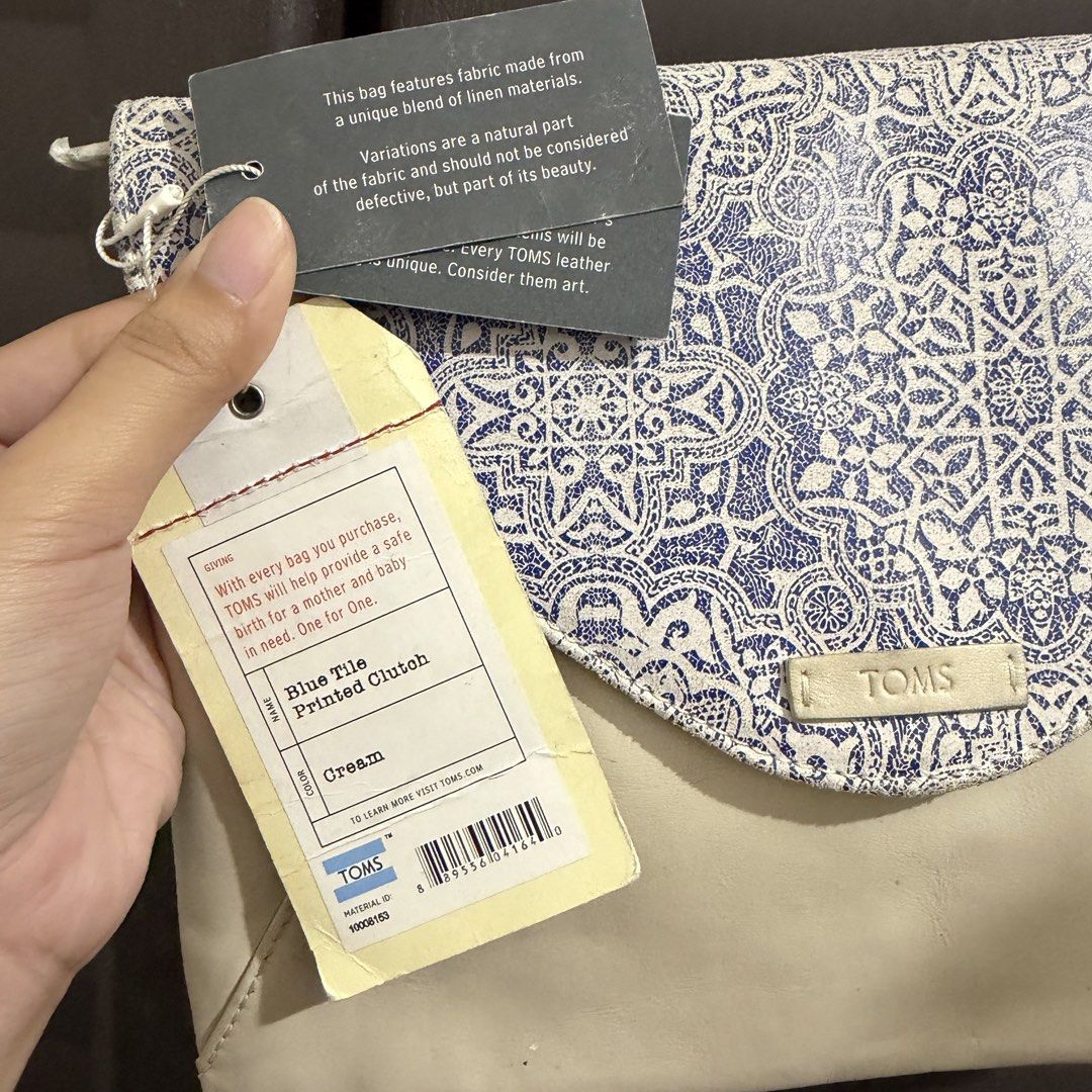 TOMS Blue Tile Printed Clutch Cream (Category: Clutches) located in Rizal. Submitted by lovegclothingph (Listing ID 1469886444, Image 3). Description: - Brand: TOMS - Condition: Brand new with tags attached - Design: Blue and white tile-printed linen flap with a cream-colored leather body - Closure: Envelope-style fold-over flap with magnetic snap and zippered main compartment - Interior: Fabric-lined with an extra zippered pocket for organizatio
