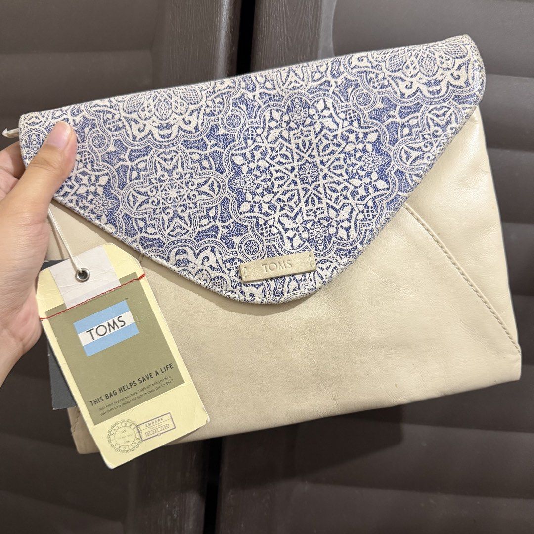 TOMS Blue Tile Printed Clutch Cream (Category: Clutches) located in Rizal. Submitted by lovegclothingph (Listing ID 1469886444, Image 1). Description: - Brand: TOMS - Condition: Brand new with tags attached - Design: Blue and white tile-printed linen flap with a cream-colored leather body - Closure: Envelope-style fold-over flap with magnetic snap and zippered main compartment - Interior: Fabric-lined with an extra zippered pocket for organizatio