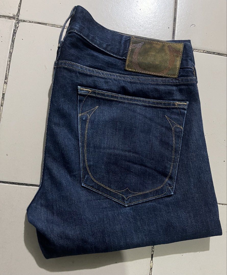 True Religion Geno (Category: Jeans) located in Cebu City. Submitted by rockall24455 (Listing ID 1469909421, Image 3). Description: - Brand: True Religion - Style: Dark wash denim jeans with standard straight leg fit - Origin: Made in USA - Size: Tagged Size 36 on interior label - Closure: Button fly - Details: Classic horseshoe back pocket stitching and leather back patch - Condition: Clean denim fabric, ready to wear.