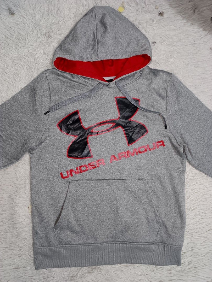 Under Armour Grey and Red Hoodie Size Medium (Category: Hoodies) located in Angeles City. Submitted by analizabag92980 (Listing ID 1469823441, Image 2). Description: - Brand: Under Armour - Color: Grey with vibrant red hood lining and drawstrings - Size: Medium (Measures 22" x 27" inches) - Design: Large black and red chest graphic with lettering - Features: Front kangaroo pocket, ribbed cuffs, and hem - Condition: Excellent ready-to-wear conditi