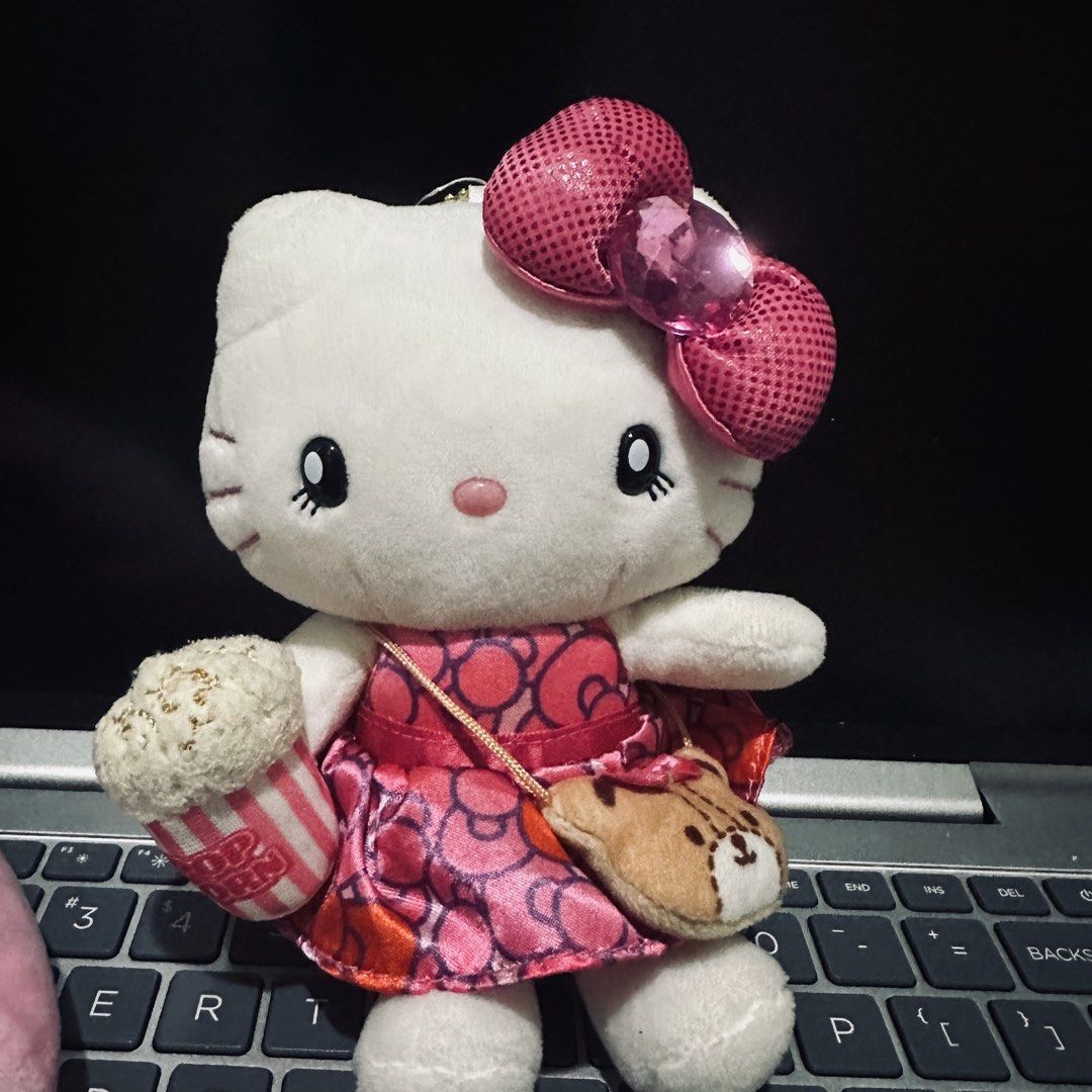 Universal Studios Japan Hello Kitty Plush Toy with Popcorn Bag (Category: Plushies & Soft Toys) located in Makati City. Submitted by reinboo_collection (Listing ID 1469886036, Image 1). Description: - Authentic Universal Studios Japan (USJ) Kitty plush toy - Wears a stylish pink patterned dress and glittery pink bow with a large gem - Holds a cute popcorn bucket and wears a small stuffed crossbody pouch - Versatile back attachment with both a bal