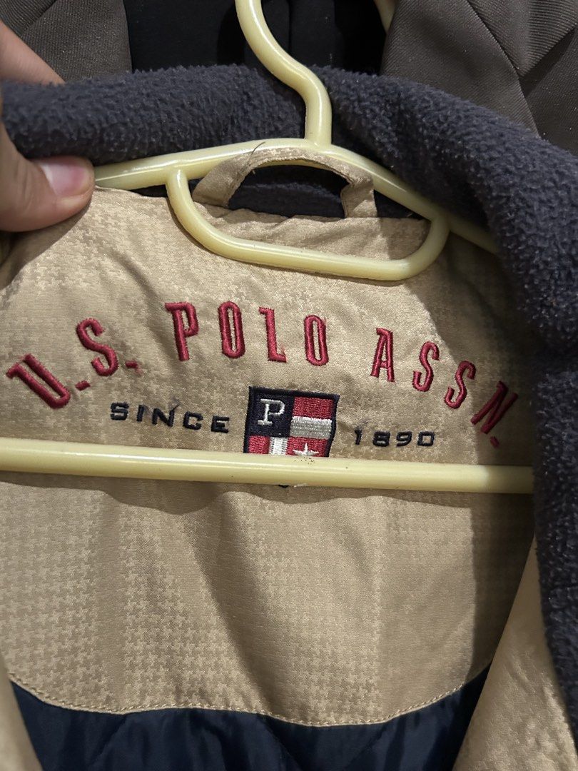 U.S. Polo Assn. Khaki Winter Jacket (Category: Coats, Jackets and Outerwear) located in Ozamiz City. Submitted by kkaier7777 (Listing ID 1469776294, Image 2). Description: - Brand: U.S. Polo Assn. - Color: Khaki exterior with quilted navy blue inner lining - Collar: Dark fleece collar with embroidered logo lettering inside - Closure: Full zip front with button-flap - Features: Practical front pockets - Condition/Material: Thick, heavy-duty outerw