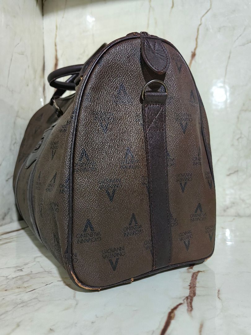 Valentino Brown Monogram Travel Duffel Bag (Category: Luxury Bags & Wallets) located in Tarlac. Submitted by jeremiah.curator.2026 (Listing ID 1469768730, Image 2). Description: - Brand: Valentino - Color/Design: Dark brown with all-over monogram print and leather-look trim - Hardware: Gold-tone accents on handle connector rings - Closure: Secure top zip - Features: Side rings for optional shoulder strap attachment - Capacity: Generous size, idea