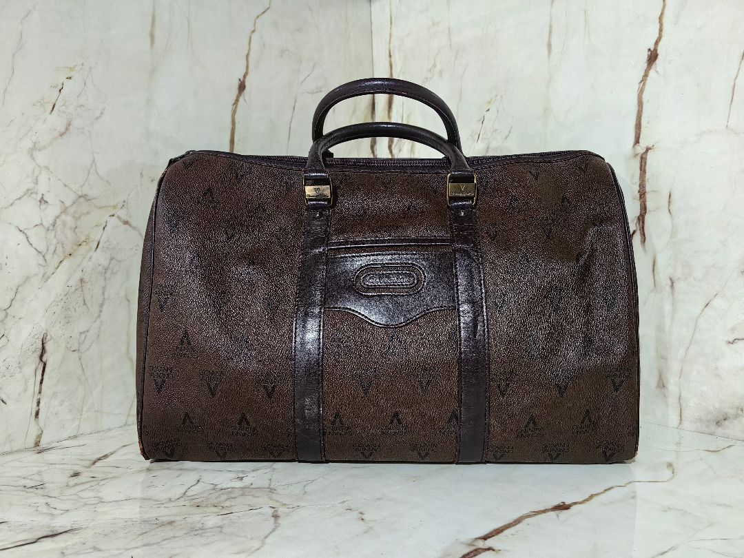 Valentino Brown Monogram Travel Duffel Bag (Category: Luxury Bags & Wallets) located in Tarlac. Submitted by jeremiah.curator.2026 (Listing ID 1469768730, Image 1). Description: - Brand: Valentino - Color/Design: Dark brown with all-over monogram print and leather-look trim - Hardware: Gold-tone accents on handle connector rings - Closure: Secure top zip - Features: Side rings for optional shoulder strap attachment - Capacity: Generous size, idea