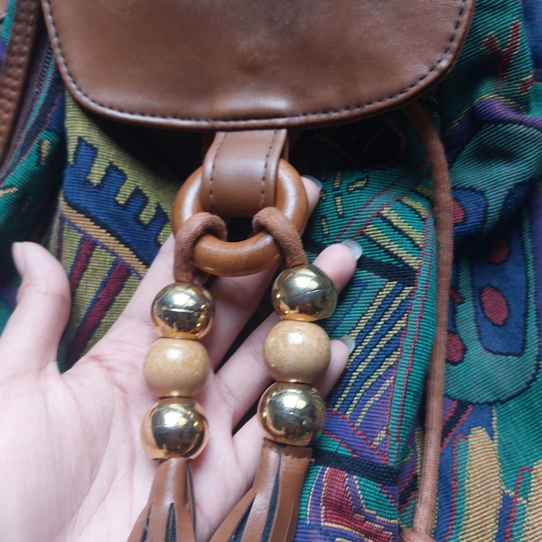 Vintage Boho Tapestry and Brown Leather Backpack (Category: Backpacks) located in Manila. Submitted by youresovaiineee (Listing ID 1469847492, Image 3). Description: - Vintage statement backpack with colorful woven tapestry fabric and brown leather trim - Secure drawstring and magnetic snap flap closure - Stylish wooden ring detail with wooden and metallic gold bead tassels - Adjustable shoulder straps for a comfortable fit - Handy side zipper po