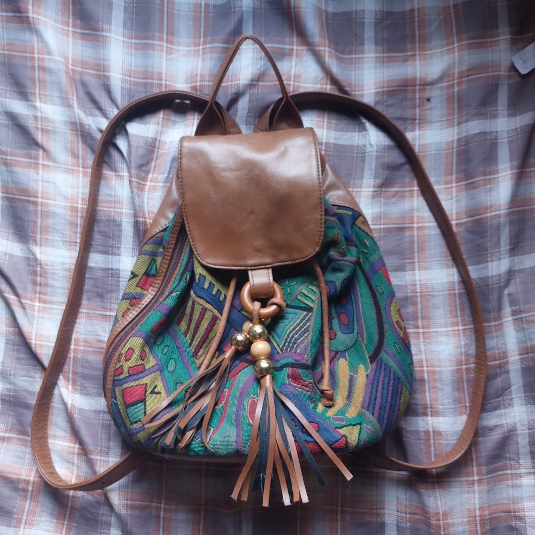 Vintage Boho Tapestry and Brown Leather Backpack (Category: Backpacks) located in Manila. Submitted by youresovaiineee (Listing ID 1469847492, Image 1). Description: - Vintage statement backpack with colorful woven tapestry fabric and brown leather trim - Secure drawstring and magnetic snap flap closure - Stylish wooden ring detail with wooden and metallic gold bead tassels - Adjustable shoulder straps for a comfortable fit - Handy side zipper po