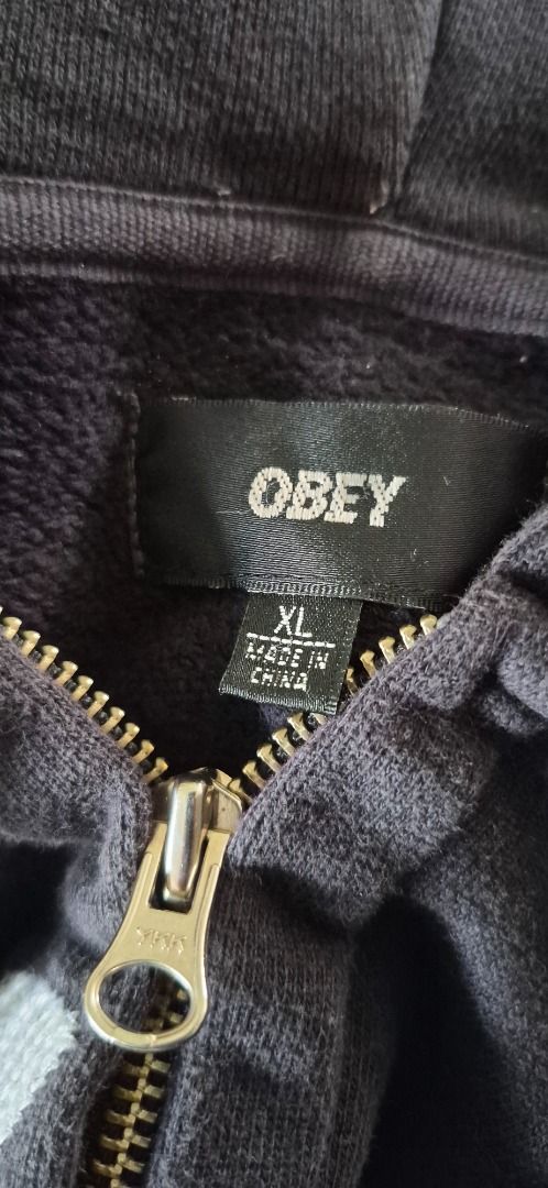 Vintage OBEY Script / Cursive Logo Full-Zip Hoodie (Category: Coats, Jackets and Outerwear) located in Taguig. Submitted by regimennn (Listing ID 1469846844, Image 2). Description: - Brand: Obey Vintager Script Skating Oversized Hoodie - Style: Zip-up hoodie with drawstring - Color: Black with large white script logo across the chest - Size: XL - Material: 100% cotton - Hardware: Durable YKK full metal zip.