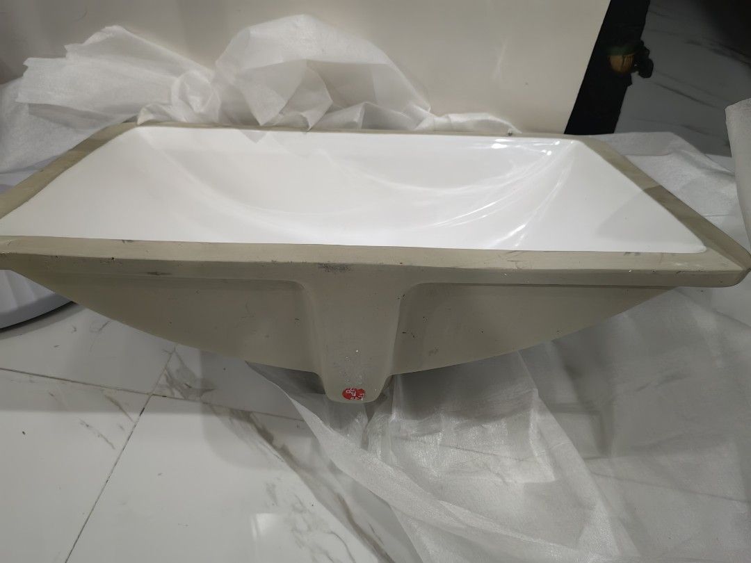 White Ceramic Undermount Bathroom Sink Basin (Category: Bathroom & Kitchen Fixtures) located in Santa Rosa. Submitted by aeonflux_girl08 (Listing ID 1469821000, Image 2). Description: - Type: Rectangular undermount sink - Finish: Glossy white ceramic - Style: Clean minimalist look, ideal for modern bathroom vanities - Drain Hole: Standard size, positioned on the side - Condition: Heavy duty basin, still with original edge protective packaging, re