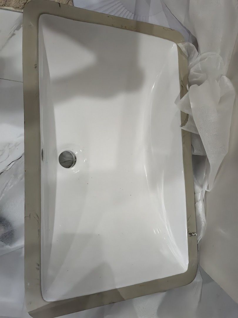 White Ceramic Undermount Bathroom Sink Basin (Category: Bathroom & Kitchen Fixtures) located in Santa Rosa. Submitted by aeonflux_girl08 (Listing ID 1469821000, Image 1). Description: - Type: Rectangular undermount sink - Finish: Glossy white ceramic - Style: Clean minimalist look, ideal for modern bathroom vanities - Drain Hole: Standard size, positioned on the side - Condition: Heavy duty basin, still with original edge protective packaging, re