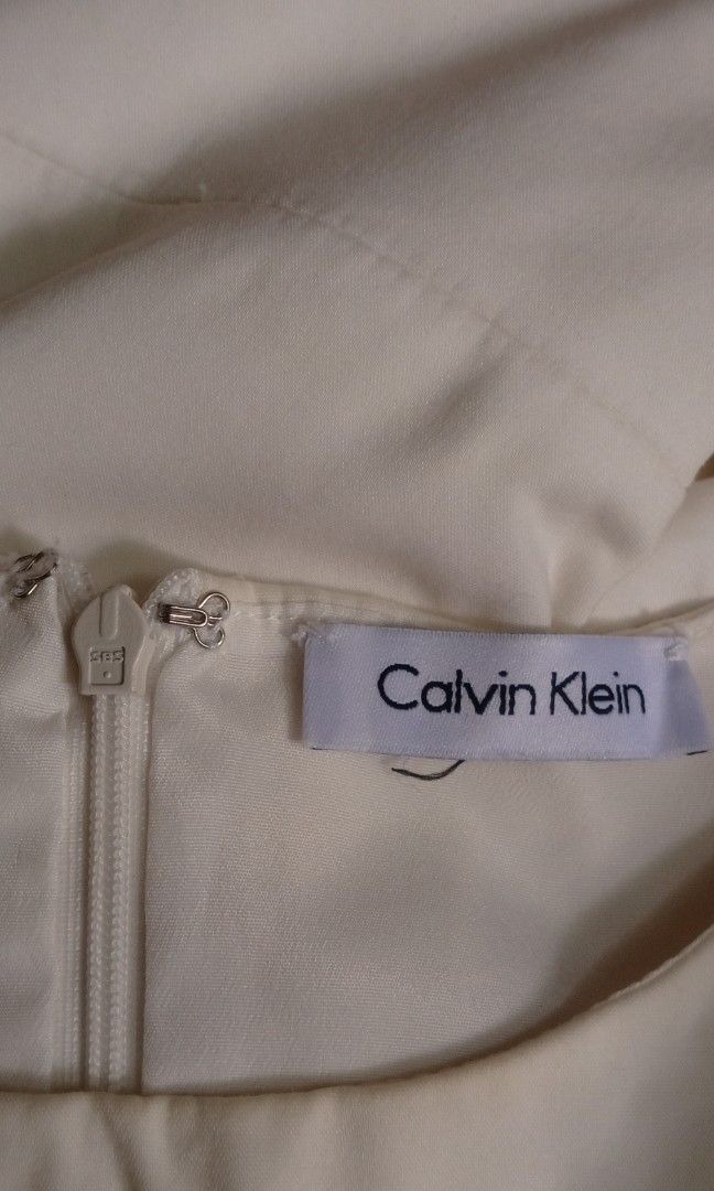 Calvin Klein White Cold Shoulder Midi Dress with Lantern Sleeves (Category: Dresses) located in Manila. Submitted by charlottej01596 (Listing ID 1469783439, Image 2). Description: - Style: White midi dress with a sleek, solid color - Sleeves: Dramatic lantern sleeves with ribbon wrist ties and trendy cold shoulder cutouts - Fit: Crew neckline, fitted waist seam, and slight A-line skirt - Closure: Convenient back zipper - Material: Smooth, comfort