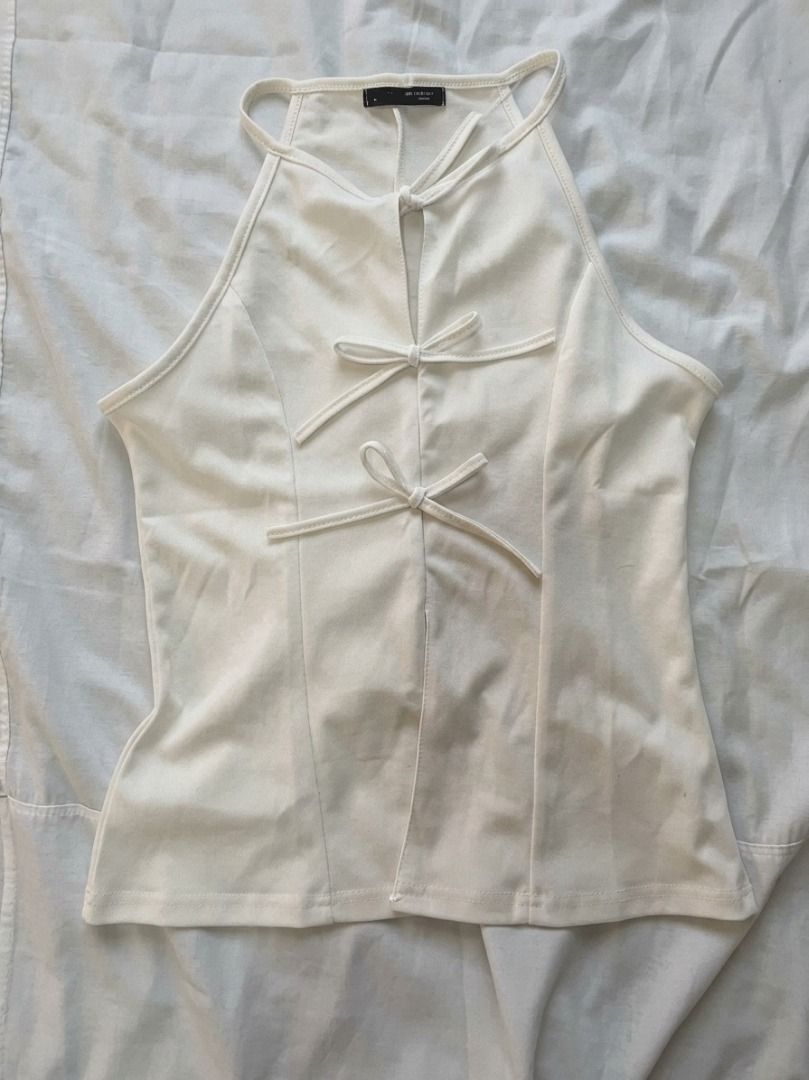 White Halter Top with Bow Accents (Category: Sleeveless) located in Bacoor. Submitted by maycee.rafallo (Listing ID 1469801122, Image 1). Description: - Color: White - Style: Sleeveless halter top with a fitted cut - Details: Three charming decorative ribbon bows down the front center split - Fabric: Lightweight and comfortable - Versatility: Great for layering or wearing on its own; easy to pair with high-waisted jeans or skirts - Condition: Bra