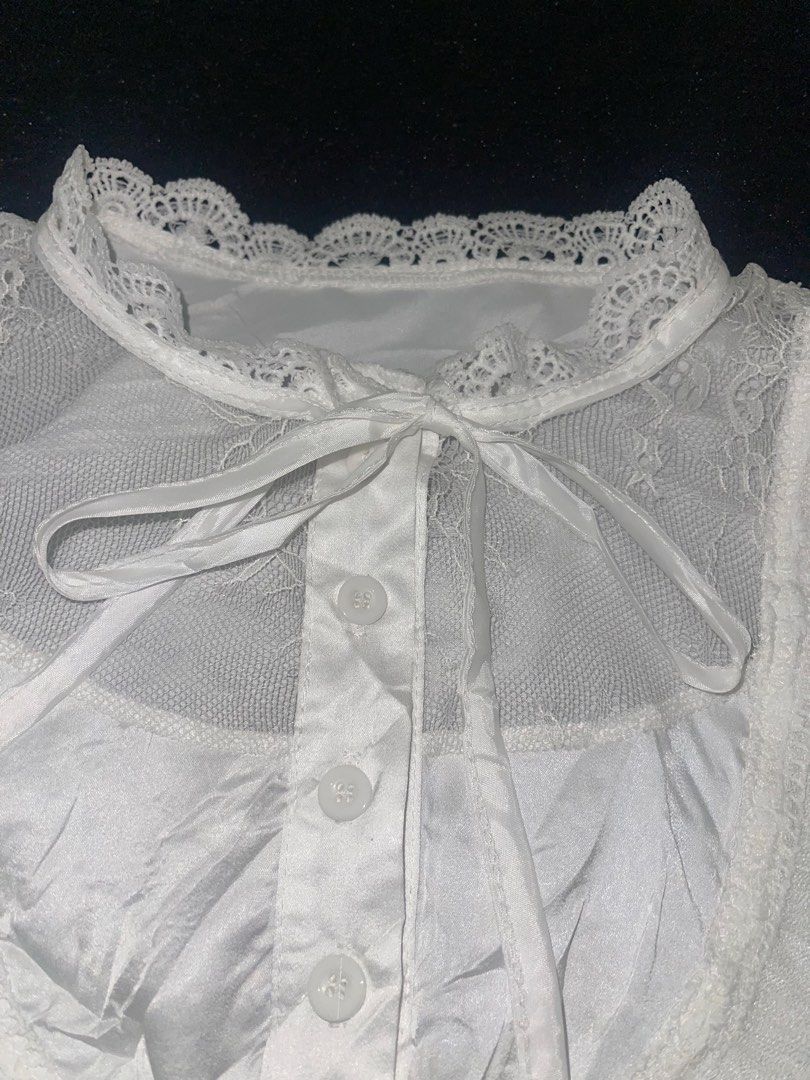 White lace trim ruffle blouse long sleeve (Category: Longsleeves) located in La Trinidad. Submitted by potatothriftlip (Listing ID 1469871120, Image 2). Description: - Style: Romantic vintage, ideal for Lolita and Gothic fashion - Design: Button-up front with a soft satin-like body fabric - Details: Sheer mesh neckline, delicate lace collar, and tiered lace cuffs - Accents: Includes a matching ribbon tie at the collar - Condition: Brand new/Mint 