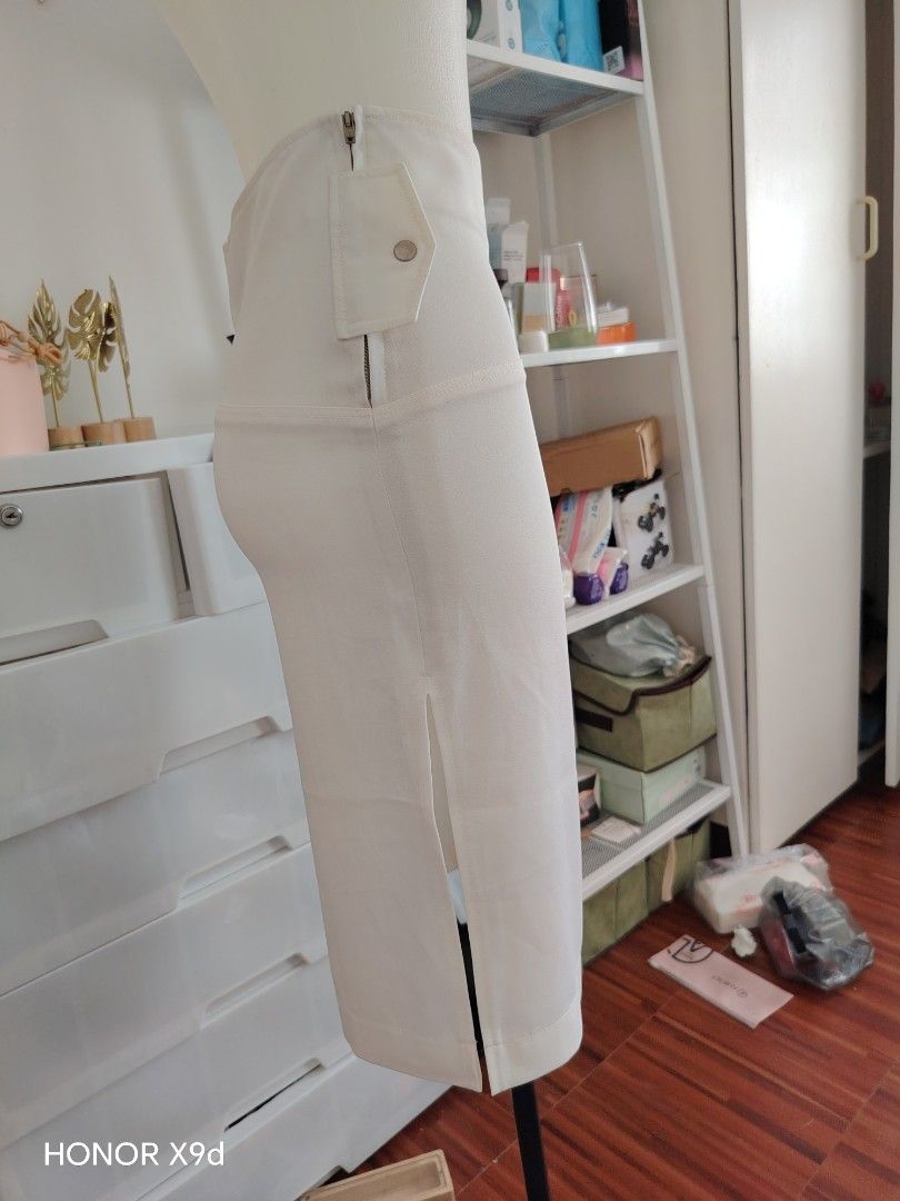 White midi skirt with side zipper and split (Category: Skirts) located in Mabalacat. Submitted by Jackikay.PreLoved (Listing ID 1469824438, Image 2). Description: - Size: S on tag - Color: Clean White - Length: Midi / Mid-calf - Waist: High waist design - Details: Asymmetrical front overlay, side slit - Closure: Side metal zipper with button snap flap - Material: Structured fabric.