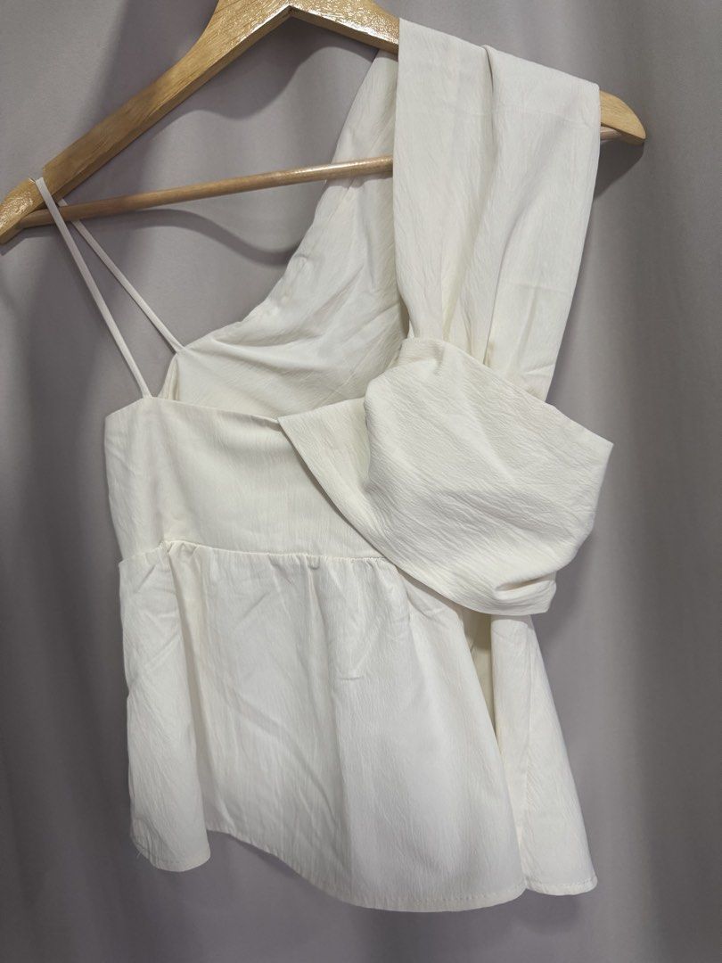 White One-Shoulder Asymmetric Peplum Top (Category: Sleeveless) located in Manila. Submitted by decluterthings888 (Listing ID 1469822905, Image 1). Description: - Color: White - Material: Textured crinkle fabric - Design: One-shoulder with an asymmetric drape and thin strap - Fit: Fitted bodice with a flattering gathered peplum hem - Styling: Perfect for casual days out, easily pairs with jeans or skirts.