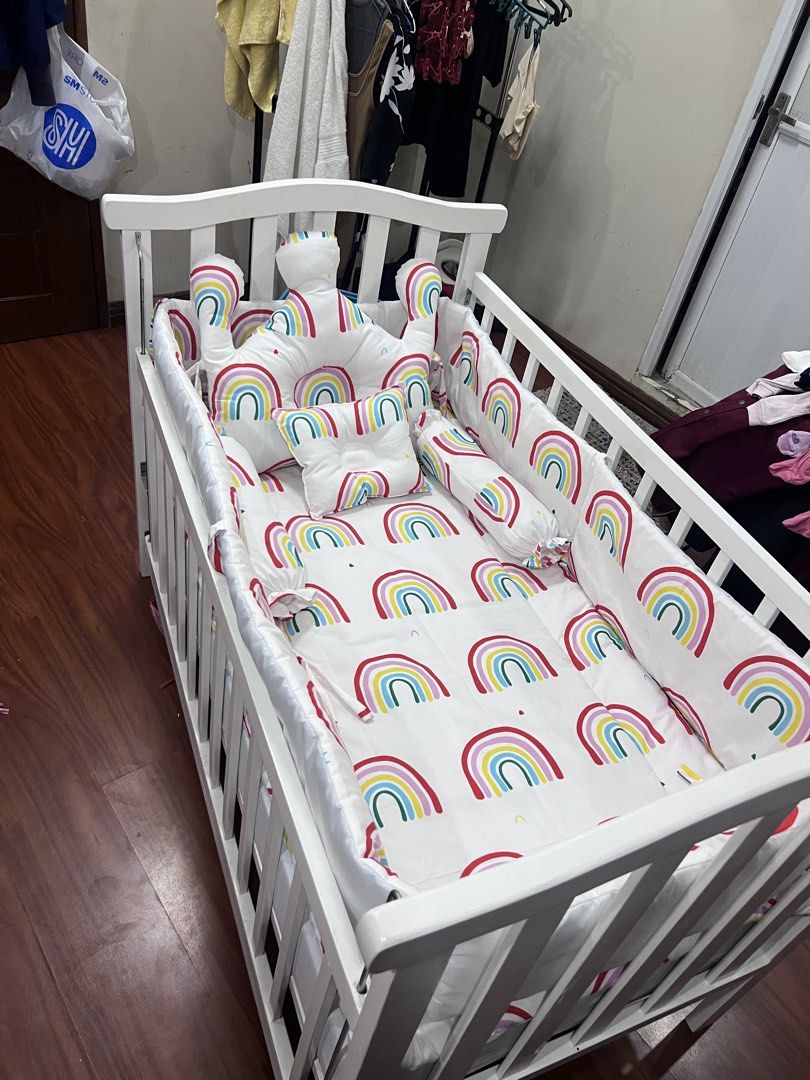 White Wooden Baby Cot with Rainbow Bedding Set (Category: Cots & Cribs) located in Bulacan. Submitted by nicolecab03210 (Listing ID 1469933250, Image 1). Description: - White wooden baby crib with a sturdy slatted design - Complete bedding set with fun rainbow prints - Includes a matching crown-shaped headboard pillow - Comes with side bumper pads and a small square pillow - Clean, well-maintained, and ready for nursery use Crib Set For sale Crib