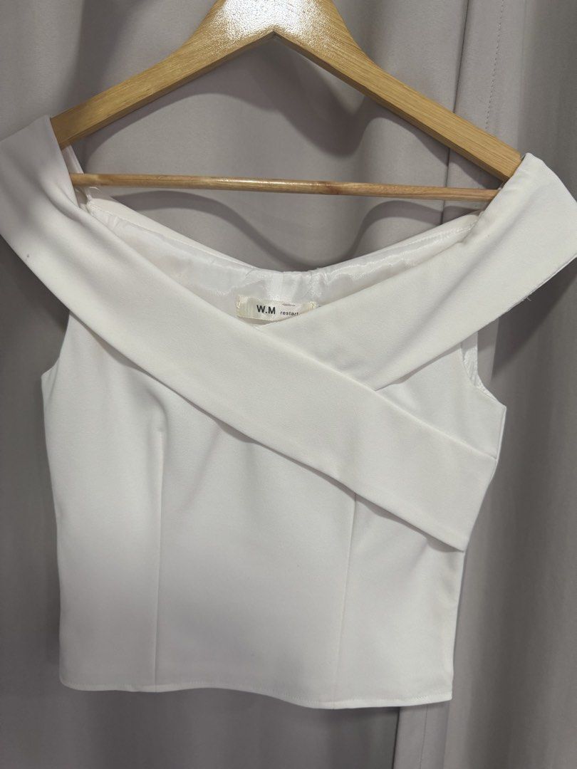 W.M restart white off-shoulder cross-strap top (Category: Blouses) located in Manila. Submitted by decluterthings888 (Listing ID 1469822805, Image 1). Description: - Brand: W.M restart - Style: Off-shoulder crop top with diagonal front cross-strap - Details: Structured material and flattering front seams - Color: Clean white - Fit & Pairing: Great fit, perfect to match with high-waisted pants or skirts - Condition: Excellent, chic, and trendy.
