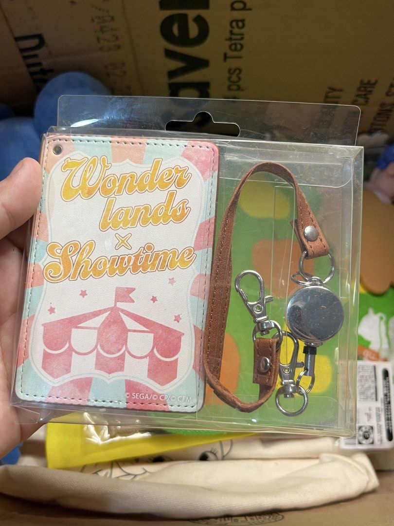 Wonderlands x Showtime Pass Case Card Holder (Category: Wallets & Card holders) located in Gapan. Submitted by lunashop14 (Listing ID 1469830824, Image 1). Description: - Authentic Wonderlands x Showtime pass case / card holder from Project Sekai - Front design features an adorable pastel circus tent graphic - Back is made of stylish brown faux leather - Comes with a matching brown strap, retractable reel, and convenient lobster clasp hooks - Bra