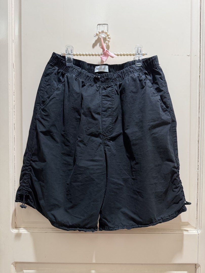 ZARA Black Drawstring Parachute Shorts (Category: Shorts) located in Davao. Submitted by 2ndbase.dvo.ii (Listing ID 1469928689, Image 2). Description: - Brand: ZARA - Color: Black - Size: L (EUR L, USA L, MEX 30) - Material: Lightweight and breathable - Fit: Relaxed, knee-length cut - Waistband: Elastic with adjustable drawstring toggle - Features: Adjustable cinched drawstrings on sides for leg opening, deep side pockets - Condition: Clean insid