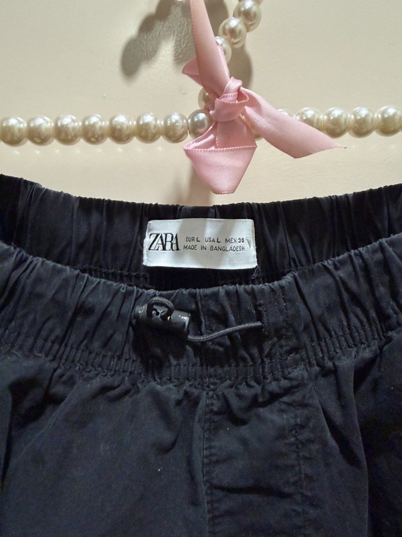 ZARA Black Drawstring Parachute Shorts (Category: Shorts) located in Davao. Submitted by 2ndbase.dvo.ii (Listing ID 1469928689, Image 3). Description: - Brand: ZARA - Color: Black - Size: L (EUR L, USA L, MEX 30) - Material: Lightweight and breathable - Fit: Relaxed, knee-length cut - Waistband: Elastic with adjustable drawstring toggle - Features: Adjustable cinched drawstrings on sides for leg opening, deep side pockets - Condition: Clean insid