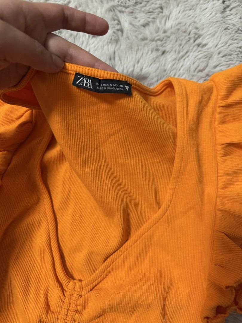 Zara Orange Ruffle Sleeves Ruched Crop Top (Category: Sleeveless) located in Calamba. Submitted by cheriiv (Listing ID 1469895234, Image 2). Description: - Brand: Zara - Size: S - Color: Bright orange - Material: Soft and stretchy ribbed fabric - Design: V-neckline with adjustable drawstring ruching in the front - Details: Cute ruffled cap sleeves on both shoulders - Condition: Excellent.