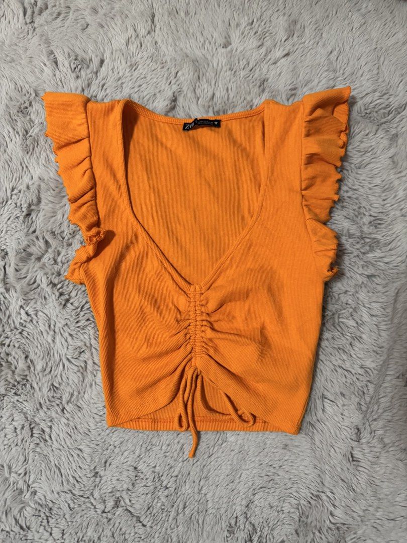Zara Orange Ruffle Sleeves Ruched Crop Top (Category: Sleeveless) located in Calamba. Submitted by cheriiv (Listing ID 1469895234, Image 1). Description: - Brand: Zara - Size: S - Color: Bright orange - Material: Soft and stretchy ribbed fabric - Design: V-neckline with adjustable drawstring ruching in the front - Details: Cute ruffled cap sleeves on both shoulders - Condition: Excellent.