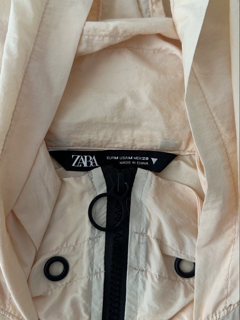 Zara Peach Cropped Windbreaker Jacket Size M (Category: Coats, Jackets and Outerwear) located in Manila. Submitted by denise805 (Listing ID 1469886479, Image 3). Description: - Brand: Zara - Style: Cropped windbreaker - Size: M - Color: Peach with contrasting black details - Features: Half-zip closure with ring pull, hooded neckline, grommet details, gathered seam accents - Cuffs & Hem: Black ribbed for a snug fit - Material: Lightweight, easy to