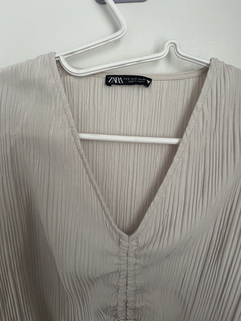 Zara Ruched Top (Category: Longsleeves) located in Lapu Lapu. Submitted by alexisdeclutters (Listing ID 1469787092, Image 2). Description: - Brand: Zara - Color: Beige - Size: S - Design: All-over pleats, V-neckline with adjustable drawstring tie - Details: Long sleeves with gathered cuffs, cropped fit - Condition: Brand new with tag attached.