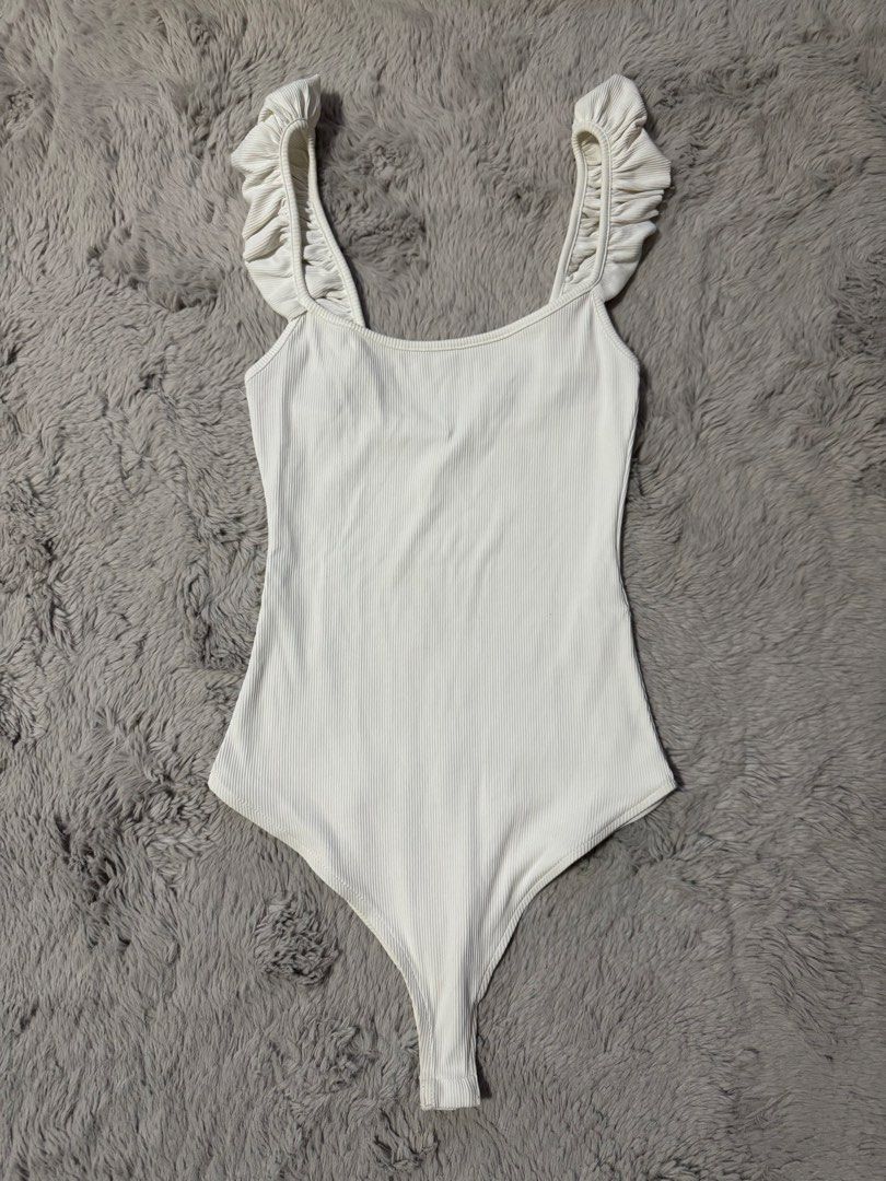 Zara Ruffled Strap Ribbed Bodysuit White (Category: Sleeveless) located in Calamba. Submitted by cheriiv (Listing ID 1469883391, Image 1). Description: - Brand: Zara - Style: White ribbed bodysuit with square neckline and thick ruffle straps - Size: Small - Details: Snap button closure at the bottom, made in Portugal - Material: Stretchy cotton blend.