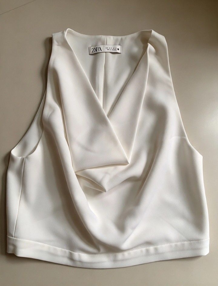 Zara White Cowl Neck Crop Top (Category: Sleeveless) located in Manila. Submitted by charlottej01596 (Listing ID 1469793676, Image 2). Description: - Brand: Zara - Color: Clean White - Style: Sleeveless semi crop top with draped cowl neckline - Details: Structured folds at front and back, wide finished hem - Condition: Excellent, lightweight fabric with clean tag, no stains or pulls.