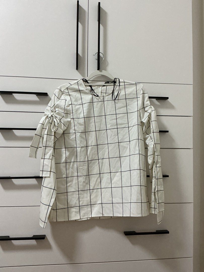 Zara Woman Grid Blouse (Category: Blouses) located in Quezon City. Submitted by cade.ph (Listing ID 1469872282, Image 1). Description: Zara Woman white long sleeve blouse featuring a stylish black grid pattern, chic bow tie cuffs, and subtle strap accents on the neckline. Lightweight, Made in Portugal, and in clean, ready-to-wear condition..