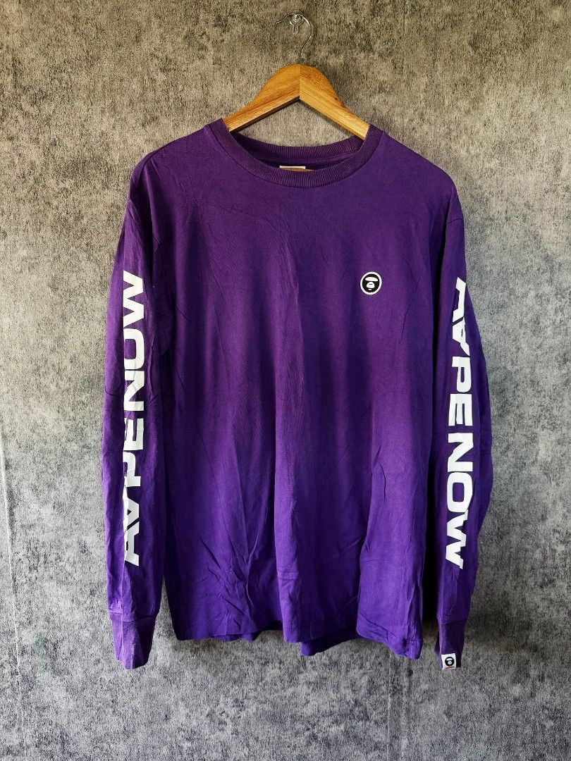 Aape Avenow Purple Long Sleeve Tee (Category: Tshirts & Polo Shirts ) located in Quezon City. Submitted by lexthrift (Listing ID 1469988428, Image 1). Description: - Brand: Aape by A Bathing Ape - Style: Purple long sleeve crewneck t-shirt - Size: Large (tag attached) - Details: Avenow text printed down both sleeves - Branding: Small Ape head logo patch on left chest and matching cuff tag - Condition: 100% authentic, well-maintained - Mode of Pay