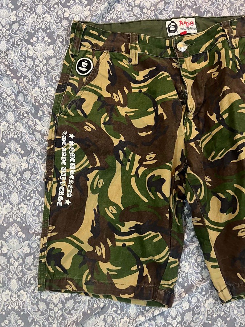 AAPE By A Bathing Ape Camo Cargo Shorts (Category: Shorts) located in Batangas. Submitted by gavsandrix (Listing ID 1470139350, Image 2). Description: - Brand: AAPE by A Bathing Ape - Design: Classic green, brown, and tan camouflage pattern - Graphics: Large white ape head skull on back right leg and vertical text print on right front pocket - Pockets: Multiple functional pockets with secure button closures - Details: Branded woven tags on waistb