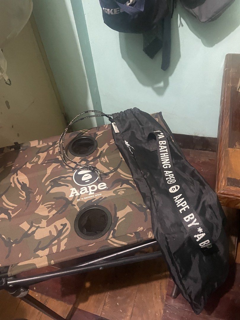 AAPE By A Bathing Ape Camo Folding Table (Category: Tables & Sets) located in Baguio. Submitted by claw_set (Listing ID 1470063624, Image 3). Description: - Authentic AAPE folding table featuring the signature camo print and bold brand logo - Built-in with 2 mesh cup holders for your drinks - Sturdy metal frame that folds down easily for quick storage and transport - Includes a black carrying bag with a branded strap and drawstring closure - Vers