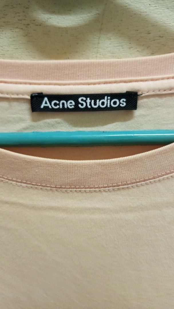 Acne Studios Face Patch Peach T-Shirt (Category: Activewear) located in Manila. Submitted by rizu09 (Listing ID 1470040080, Image 2). Description: - Brand: Acne Studios - Color: Peach (Neutral pastel tone) - Design: Iconic pink face logo patch on left chest - Fit: Relaxed fit with short sleeves - Material: 100% soft cotton for comfortable daily wear - Details: Black interior neck brand label - Condition: Excellent / As described - Mode of payment