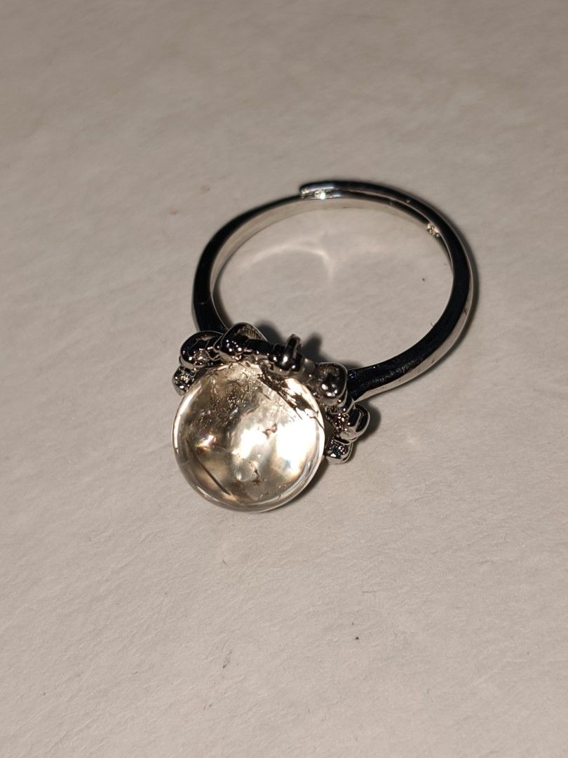 Adjustable silver ring with Clear Quartz sphere stone (Category: Rings) located in Caloocan City. Submitted by books_and_beads (Listing ID 1470090371, Image 3). Description: A beautiful, minimalist statement piece featuring a polished Clear Quartz cabochon. The domed stone has a gorgeous, glassy clarity with natural 'ice crack' inclusions that catch and reflect the light beautifully. It is set in a detailed, vintage-inspired silver-tone crown set