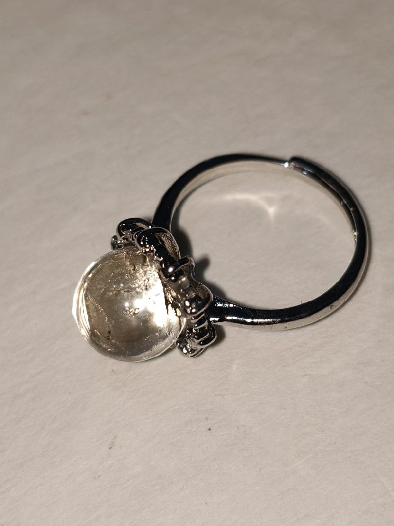 Adjustable silver ring with Clear Quartz sphere stone (Category: Rings) located in Caloocan City. Submitted by books_and_beads (Listing ID 1470090371, Image 1). Description: A beautiful, minimalist statement piece featuring a polished Clear Quartz cabochon. The domed stone has a gorgeous, glassy clarity with natural 'ice crack' inclusions that catch and reflect the light beautifully. It is set in a detailed, vintage-inspired silver-tone crown set