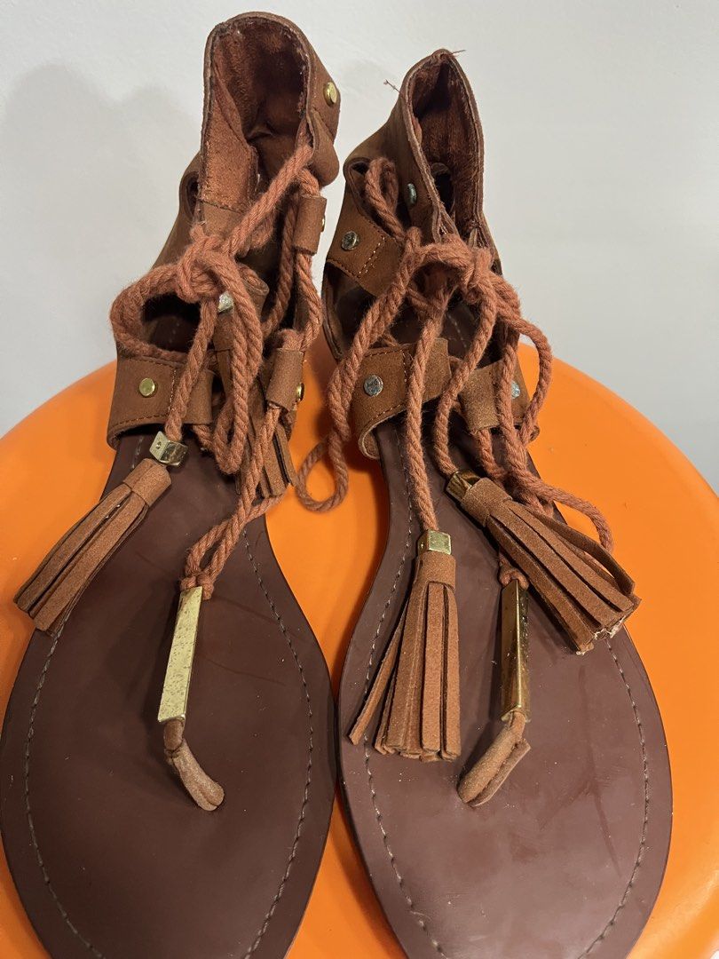 ALDO Brown Gladiator Tassel Sandals (Category: Flats & Sandals) located in Valenzuela. Submitted by sofiasticated.decluttering (Listing ID 1470056126, Image 2). Description: - Brand: ALDO - Material: Brown faux suede - Style: Flat gladiator sandals with low heels - Closure: Back zip and lace-up braided ropes with tassels and gold-tone hardware - Condition: Bottom soles show minor wear from previous use ✅PRE- OWNED and NOT suitable for picky buyer