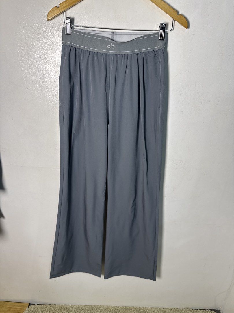 Alo Suit Up Trouser (Category: Trousers) located in Quezon City. Submitted by dropdeadprices (Listing ID 1470074517, Image 3). Description: - Brand: Alo - Style: High-waisted wide-leg trousers with pleated front - Color: Grey - Size: Large - Material: 95% modal, 5% elastane (smooth, soft, and comfortable blend) - Details: Branded elastic waistband and small white Alo logo print near the back hem - Origin: Made in Vietnam Thrifted.