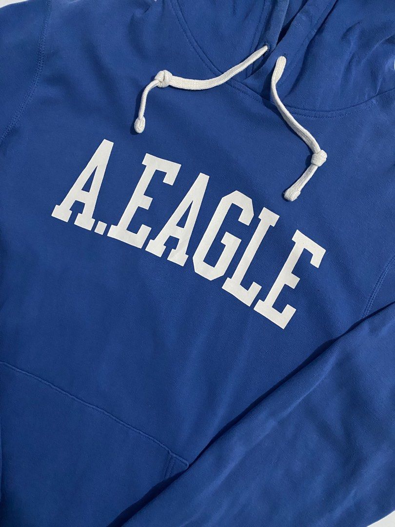 American Eagle Blue a.eagle Hoodie (Category: Coats, Jackets and Outerwear) located in San Pablo. Submitted by gt_vault (Listing ID 1470124099, Image 2). Description: Ready to wear Width: Length: Color rate: 8.5/10 Condition: Good Issue: None - Brand/Style: Authentic American Eagle hoodie in a vibrant blue color - Size: Medium with a comfortable classic fit - Design: Bold white A.EAGLE text graphic printed across the chest - Features: Adjustable 