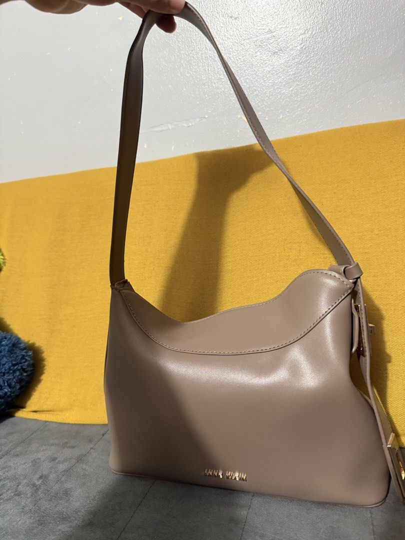 Anne Klein Taupe Shoulder Bag (Category: Shoulder Bags) located in Marikina City. Submitted by kcaps.declutter (Listing ID 1470005117, Image 2). Description: - Brand: Anne Klein - Color: Elegant taupe with gold-toned metal lettering - Material: Structured faux leather - Strap: Single matching shoulder strap with stylish side hardware - Interior: Patterned fabric lining with 1 zippered pocket and slip pockets - Condition: Clean throughout, well-ma