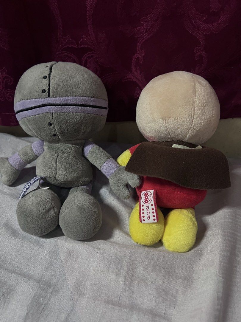 Anpanman and Robot Plush Toys Set (Category: Plushies & Soft Toys) located in Bulacan. Submitted by haven_plushie_dolls.888 (Listing ID 1470104376, Image 2). Description: - Pair of Anpanman and grey robot plushies - Sitting style with attached back tags - Anpanman wears a red and yellow outfit with a smiling button - Robot features purple limb rings and a round pink-eyed face - Crafted from soft, huggable fabric - Ideal collector's items for fans