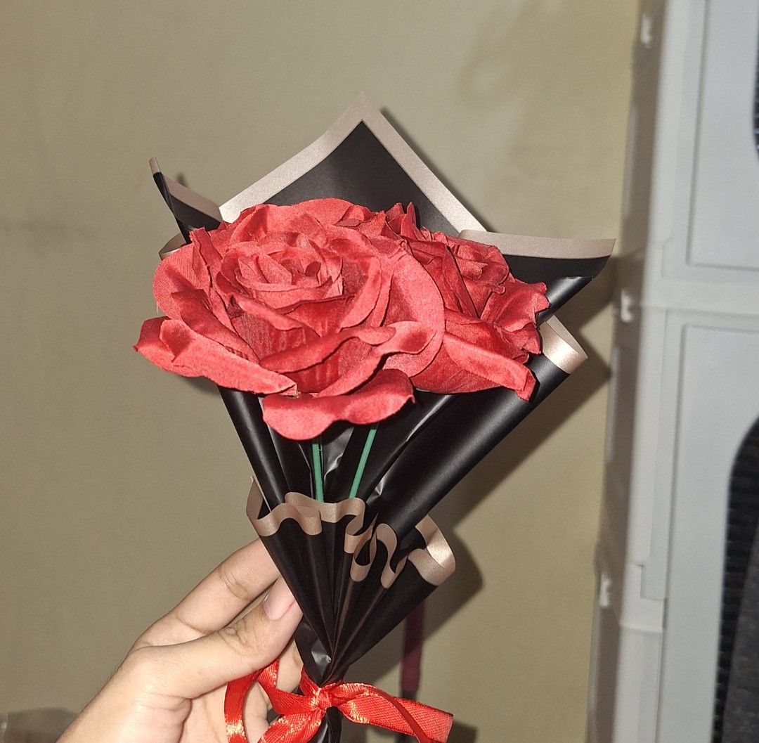 Artificial red rose bouquet with black wrapping paper (Category: Flowers & Bouquets) located in Manila. Submitted by noblegem04 (Listing ID 1470111148, Image 2). Description: - Handmade bouquet featuring three vibrant red fabric roses - Elegant black paper wrapping with stylish beige borders - Secured at the base with a bright red ribbon - Compact, one-handed size for easy handling - Perfect and ready for gifting on special occasions.