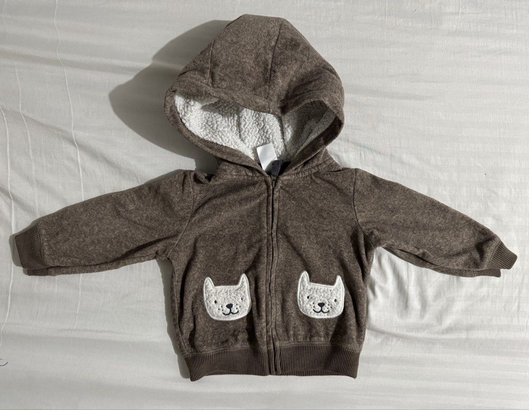 Baby Hoodie (Category: Babies & Kids Fashion) located in Paranaque City. Submitted by april_anythingpreloved (Listing ID 1470095693, Image 1). Description: - Brand: Carter's - Size: 12 months - Color: Brown with white accents - Material: Soft and warm fleece fabric - Lining: Fluffy white sherpa inside the hood - Features: Full front zipper, ribbed cuffs and hem - Details: Adorable white cat face patches on front pockets - Perfect for keeping litt